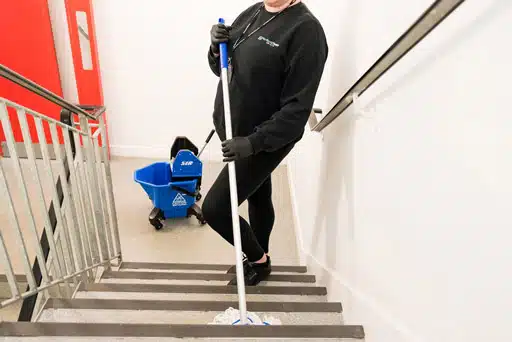 A professional cleaner delivers university cleaning services to ensure that university corridors and staircases are kept clean and safe.